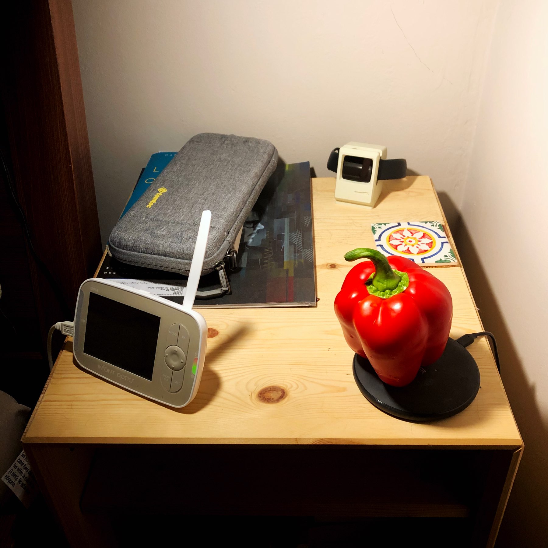 Nightstand with red pepper balanced on a phone charger.