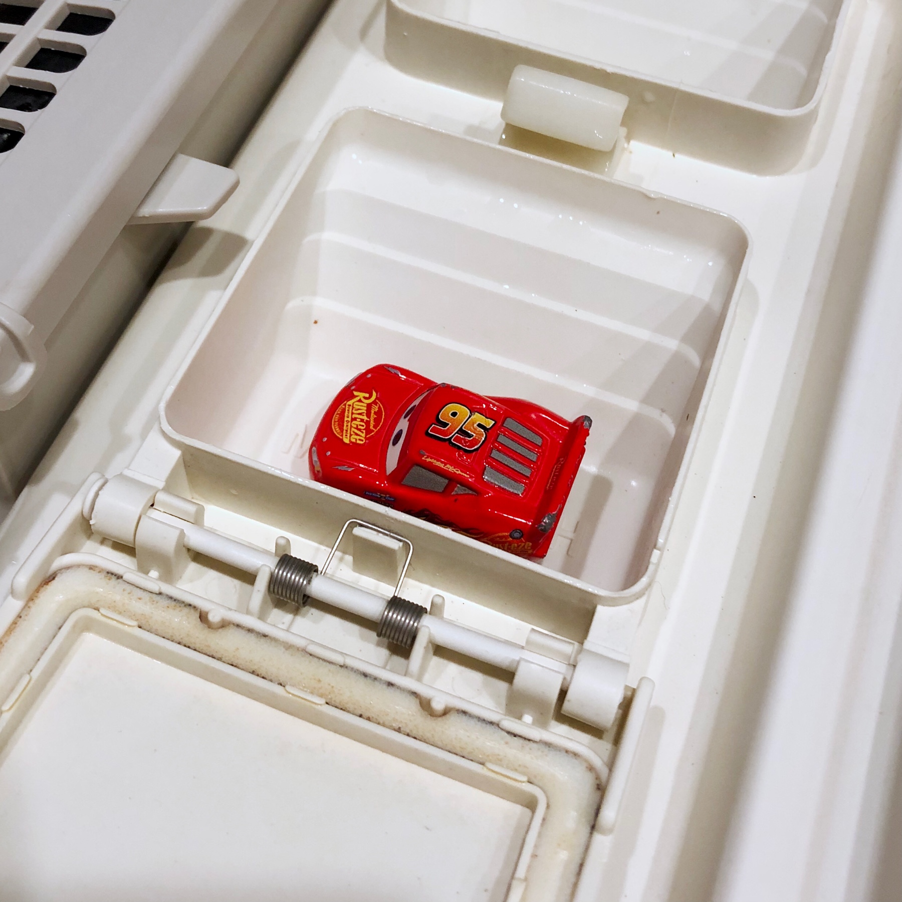 Miniture Lightning McQueen in the dishwasher soap dispenser.